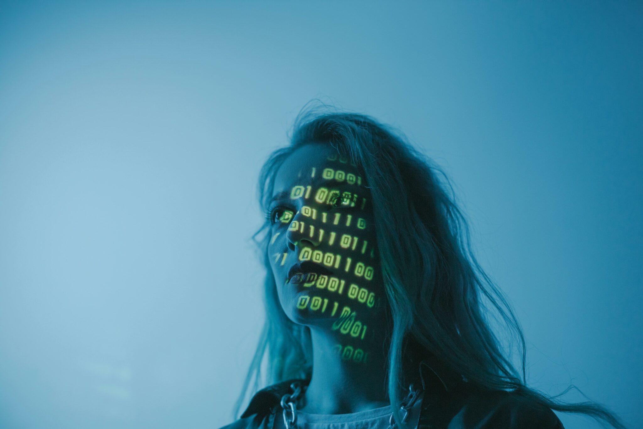 A woman with binary code lights projected on her face symbolizing technology.